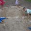 Børn leger i dinosaur sandkasse med legetøjsskeer og spande
