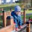 Lille dreng klatrer på legepladsudstyr i parken